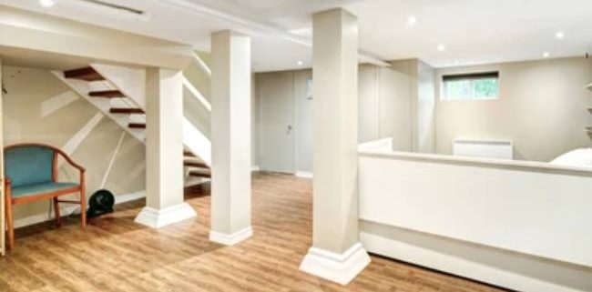 Newly-renovated basement interior with white pillars and wooden staircase